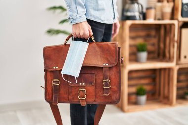 Ofiste tıbbi maske ve evrak çantası tutan İspanyol bir iş adamı.