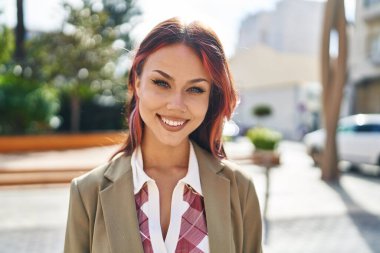 Sokakta kendine güvenen beyaz kadın gülümsüyor.