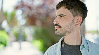 Genç İspanyol bir adam parkta ciddi bir ifadeyle yan tarafa bakıyor.