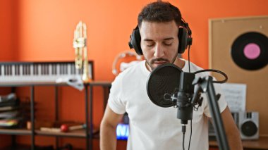 Genç Arap müzisyen müzik stüdyosunda şarkı söyleyen kulaklık takıyor.