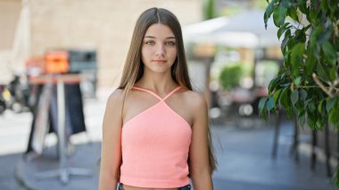 Kahve dükkanının terasında ciddi bir ifadeyle duran genç ve güzel bir kız.