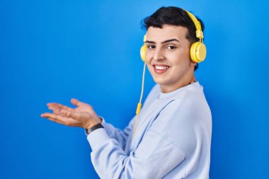 İkili olmayan kişi müzik dinlerken kulaklık kullanıyor, avuç içlerini açıp fotokopi alanını gösteriyor, gülümseyerek mutlu bir şekilde gülümsüyor. 