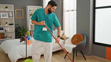 Genç İspanyol profesyonel temizlikçi yatak odasını temizliyor.