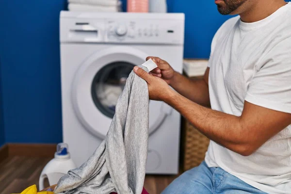 Young Hispanic Man Washing Clothes Looking Shirt Label Laundry Room — Stock Photo, Image