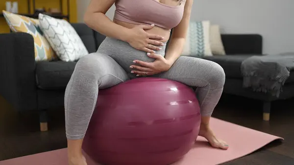 年轻的孕妇坐在适合自己的球上进行早操 — 图库照片