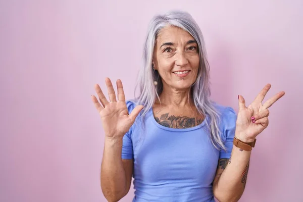Medelålders Kvinna Med Tatueringar Står Över Rosa Bakgrund Visar Och — Stockfoto