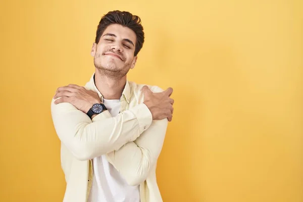Молодой Латиноамериканец Стоящий Жёлтом Фоне Обнимающий Себя Счастливым Позитивным Уверенно — стоковое фото
