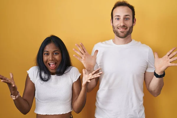 Interracial Couple Standing Yellow Background Celebrating Crazy Amazed Success Arms — Stock Photo, Image