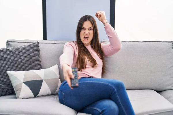 Young Brunette Woman Holding Television Remote Control Annoyed Frustrated Shouting — Stock Photo, Image