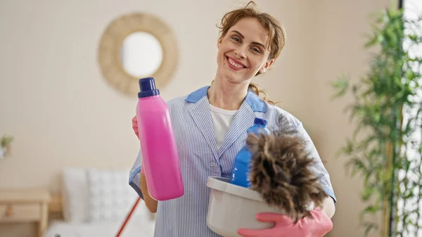 Mujer Joven Limpiadora Profesional Sosteniendo Productos Limpios Sonriendo Dormitorio —  Fotos de Stock