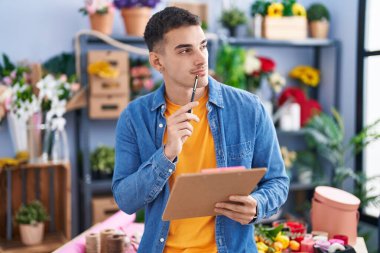 Çiçekçide, İspanyol asıllı genç bir çiçekçi kuşkuyla doküman okuyor.