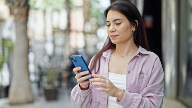 Genç ve güzel İspanyol kadın akıllı telefon kullanıyor. Sokakta ciddi bir ifadesi var.