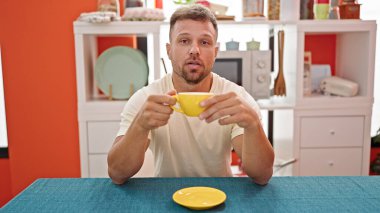 Kahve içen genç adam yemek odasında konuşuyor.