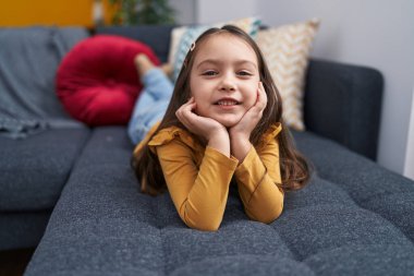 Evdeki kanepede uzanmış gülümseyen sevimli İspanyol kız.