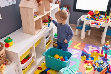 Anaokulunda rahat bir ifadeyle oynayan sevimli beyaz çocuk.