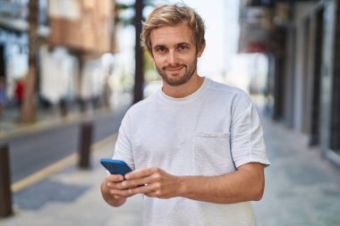 Sokakta akıllı telefon kullanan kendine güvenen genç adam.
