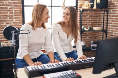 Two women musicians playing piano at music studio