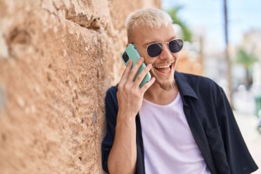 Genç beyaz adam gülümsüyor. Kendine güveniyor. Akıllı telefondan konuşuyor.