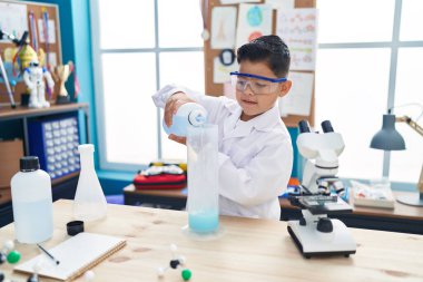 Sevimli İspanyol öğrenci laboratuvar sınıfında kendine güvenen bir öğrenci test tüpüne sıvı döküyor.