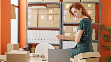 Genç kızıl saçlı kadın, iş kadını. Ofiste dizüstü bilgisayarla düşünüyor.