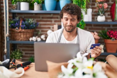 Çiçekçide dizüstü bilgisayar ve kredi kartı kullanan İspanyol bir çiçekçi.