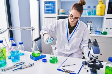 Laboratuvarda sıvıyı ölçen genç kadın bilim adamı.