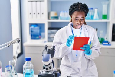 African american woman scientist using touchpad at laboratory