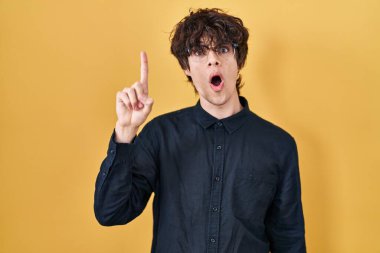 Sarı arka planda gözlük takan genç adam başarılı bir fikir olduğunu işaret ediyor. Heyecanlı ve mutlu. Bir numara.. 