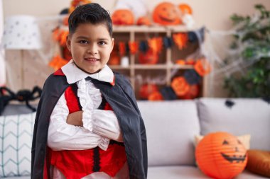 Cadılar Bayramı kostümü giyen sevimli İspanyol çocuk evde kollarını kavuşturup duruyor.