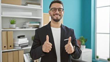 Genç Arap iş adamı ofiste baş parmak hareketi yapıyor.