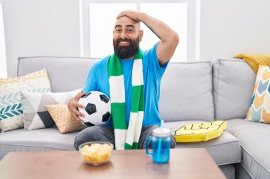 Sakallı ve dövmeli genç İspanyol adam futbol holiganı elinde top tutan destek takımı kafa kafaya, şaşırmış ve kızgın yüzüyle stresli ve hayal kırıklığına uğramış. 