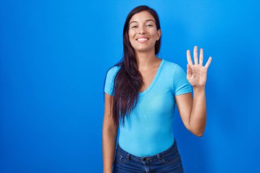 Mavi arka planda dikilen genç İspanyol kadın dört numarayı gösterip işaret ederken kendinden emin ve mutlu bir şekilde gülümsüyor.. 