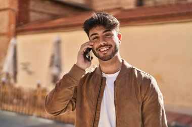 Genç İspanyol adam gülümsüyor. Kendine güveniyor. Sokakta akıllı telefondan konuşuyor.