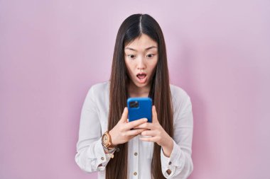 Çinli genç bir kadın akıllı telefon kullanıyor. Korku ve şaşkınlık dolu bir ifade, korku ve heyecanlı bir yüz ifadesiyle korkmuş ve şok olmuş bir şekilde mesaj yazıyor.. 