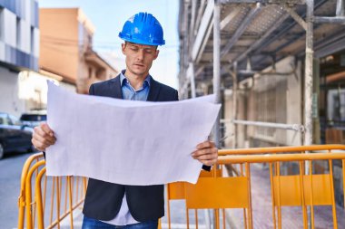 Rahat bir ifadeyle duran genç mimar sokaktaki planlara bakıyor.