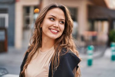 Young beautiful hispanic woman smiling confident looking to the side at street