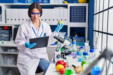 Genç ve güzel İspanyol bilim kadını. Laboratuvarda elma okuma belgesi tutuyor.