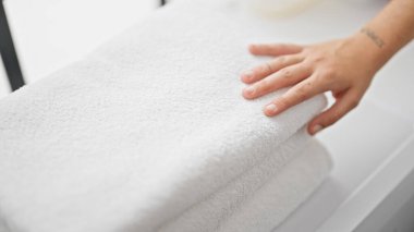 Genç ve güzel İspanyol kadın çamaşır odasında katlanmış havlulara dokunuyor.