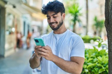 Sokakta akıllı telefon kullanan, kendine güvenen genç bir İspanyol.