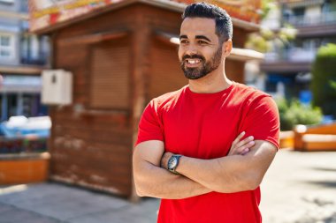 Young hispanic man smiling confident standing with arms crossed gesture at park