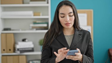 Ofiste akıllı telefon kullanan genç ve güzel bir İspanyol iş kadını.