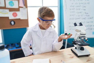 Sevimli İspanyol çocuk gülümsüyor laboratuvar sınıfında molekülleri tutan kendinden emin.