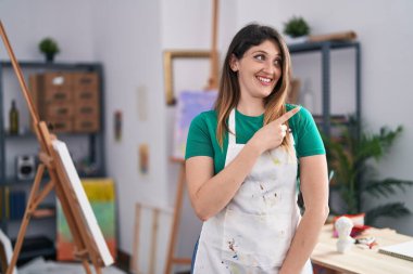 Sanat stüdyosundaki genç esmer kadın gülümsüyor. 