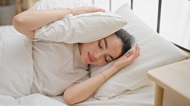 Young beautiful hispanic woman covering ears for noise at bedroom