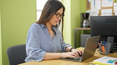 Ofiste dizüstü bilgisayar kullanan genç ve güzel bir İspanyol iş kadını.