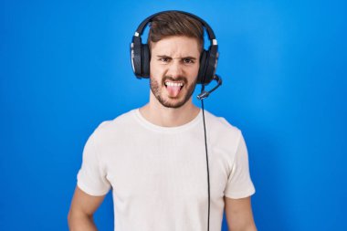 Sakallı, kulaklık takmış, komik bir ifadeyle dilini dışarı çıkaran İspanyol bir adam müzik dinliyor. duygu kavramı. 