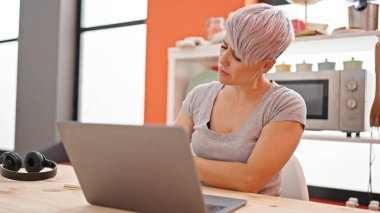 Yemek odasında dizüstü bilgisayar kullanan genç bir kadın.