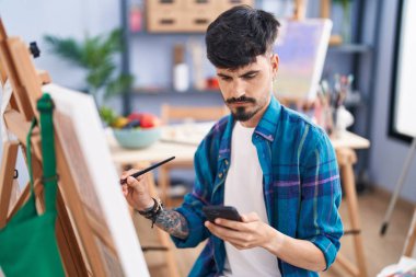 Sanat stüdyosunda akıllı telefon çizimi yapan genç bir İspanyol sanatçı.