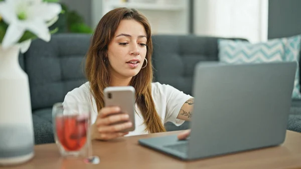 年轻美丽的惊慌失措的女人坐在家里的地板上 用笔记本电脑和智能手机 — 图库照片