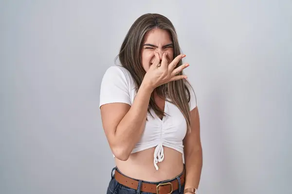 Young Beautiful Woman Wearing Casual White Shirt Smelling Something Stinky — стоковое фото